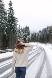 Young woman walking near snowy forest. Winter vacation