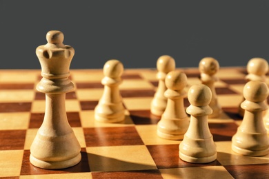 Photo of Queen and pawns on wooden chess board, closeup. Social roles concept