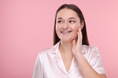 Smiling woman with dental braces on pink background. Space for text