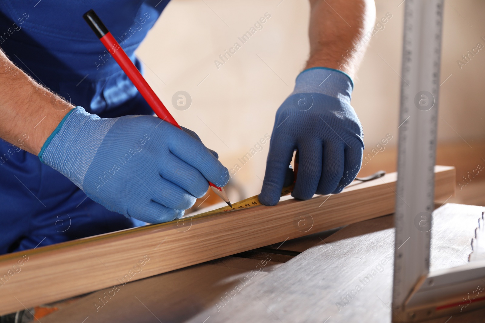 Photo of Professional carpenter making mark on wooden bar in workshop, closeup