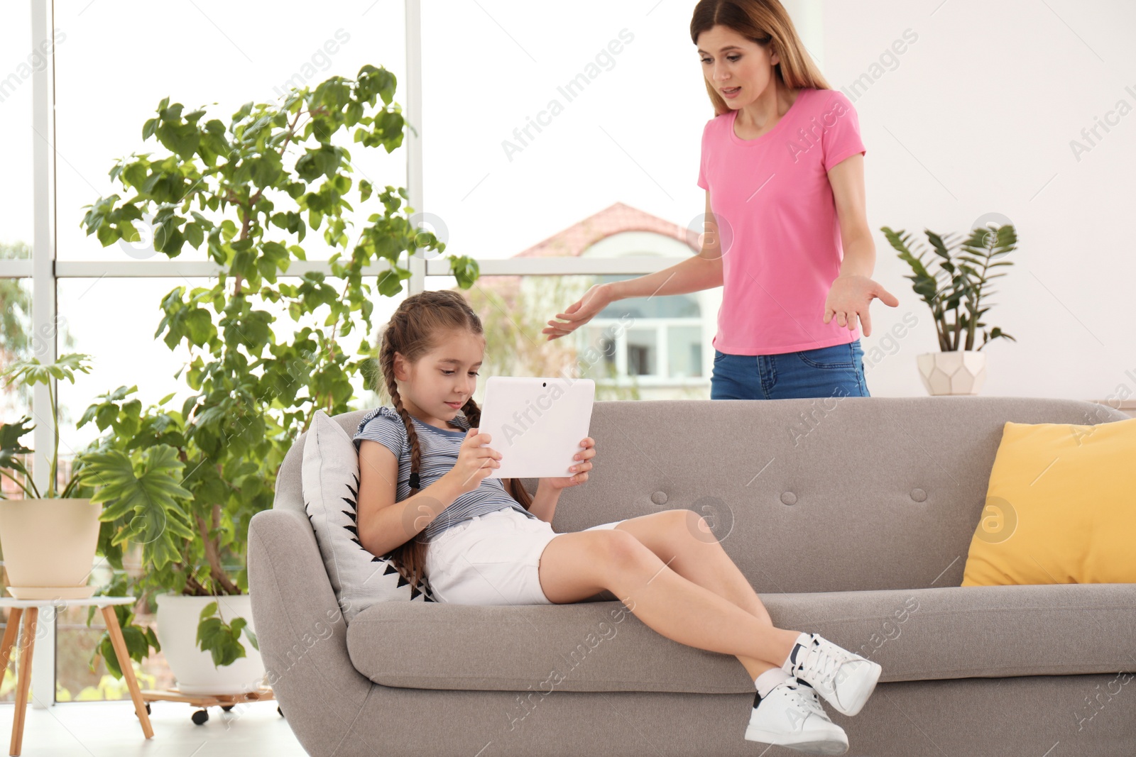 Photo of Mother scolding child while she using tablet at home. Family problems