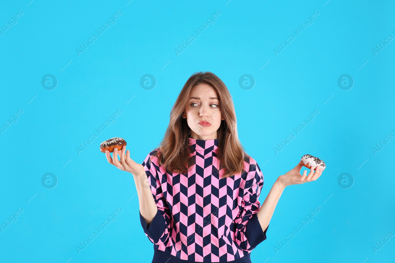 Photo of Beautiful young woman with donuts on light blue background