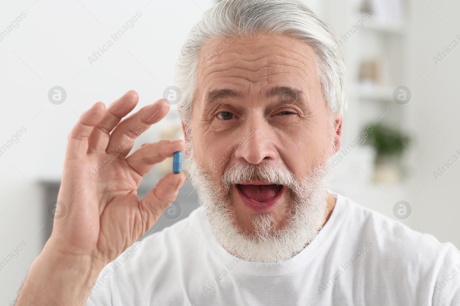 Photo of Handsome senior man with pill on blurred background