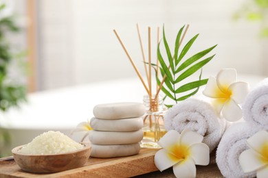 Photo of Composition with different spa products and plumeria flowers on table in bathroom, closeup