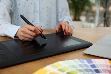 Photo of Professional designer with graphic tablet at wooden table, closeup