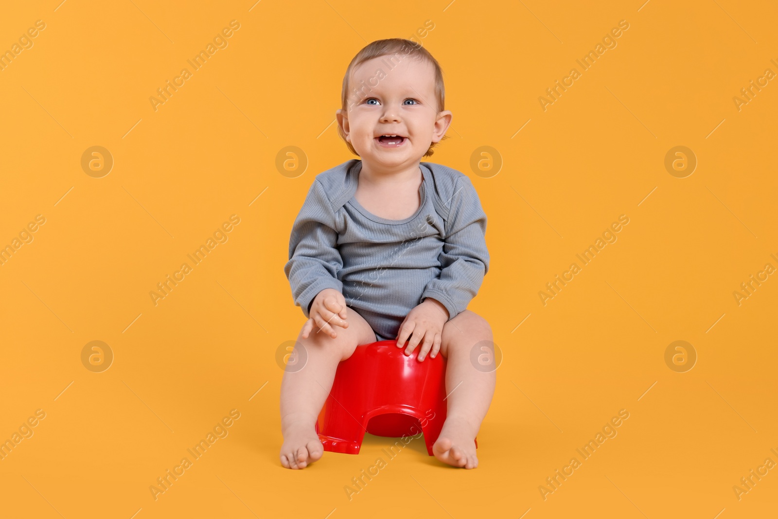 Photo of Little child sitting on baby potty against yellow background