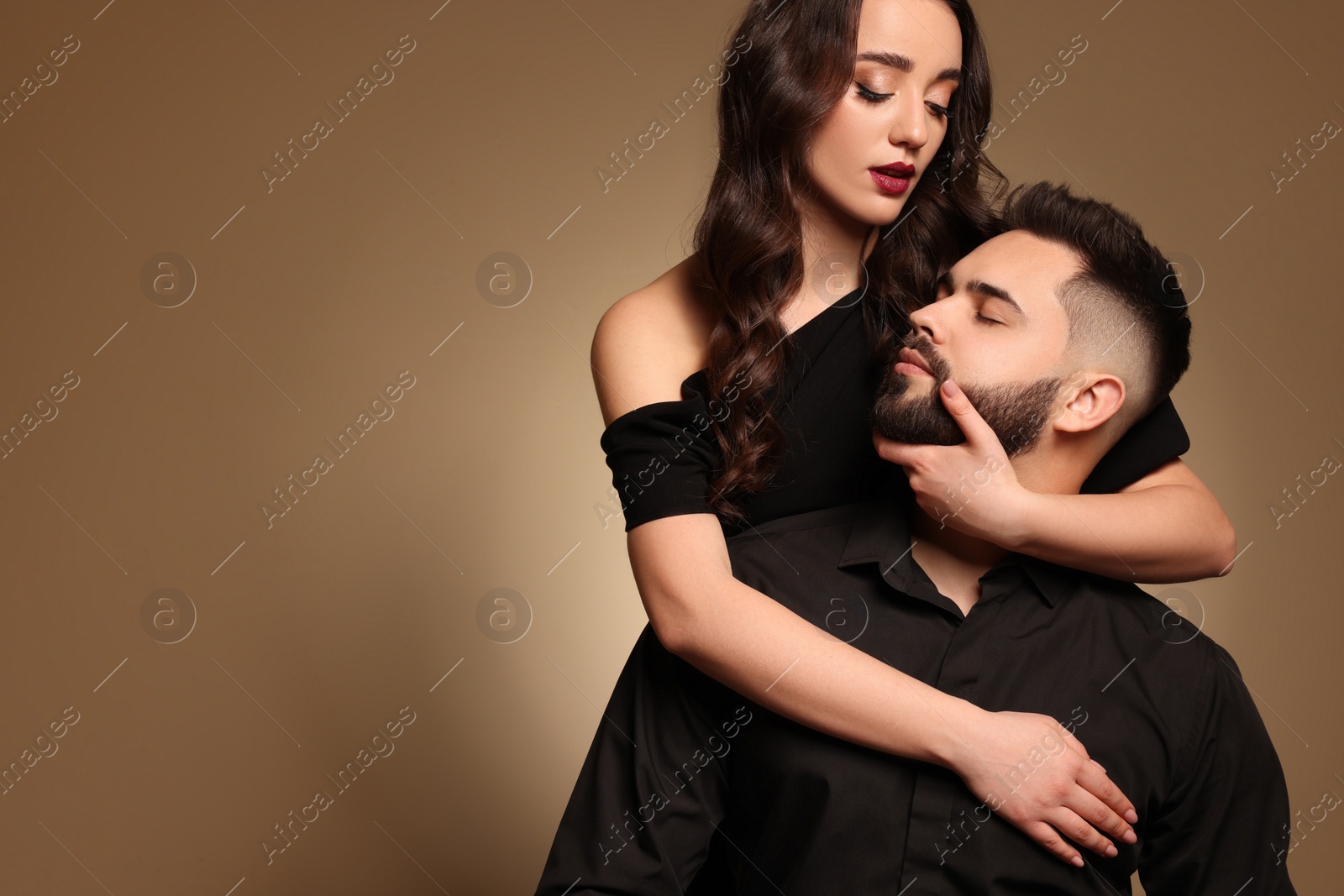 Photo of Handsome bearded man with sexy lady on light brown background. Space for text