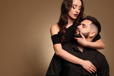 Handsome bearded man with sexy lady on light brown background. Space for text