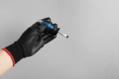 Photo of Woman holding small screwdriver on grey background, closeup. Space for text