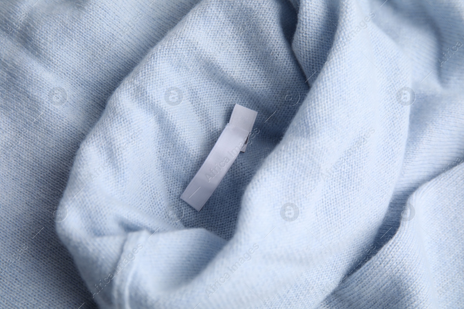 Photo of Warm light blue cashmere sweater with clothing label, closeup