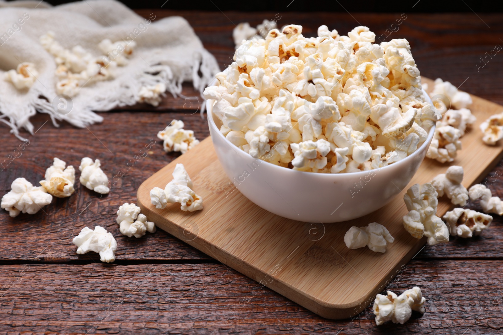 Photo of Bowl of tasty popcorn on wooden table