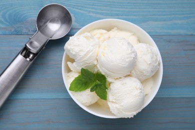 Delicious vanilla ice cream, mint and scoop on light blue wooden table, flat lay