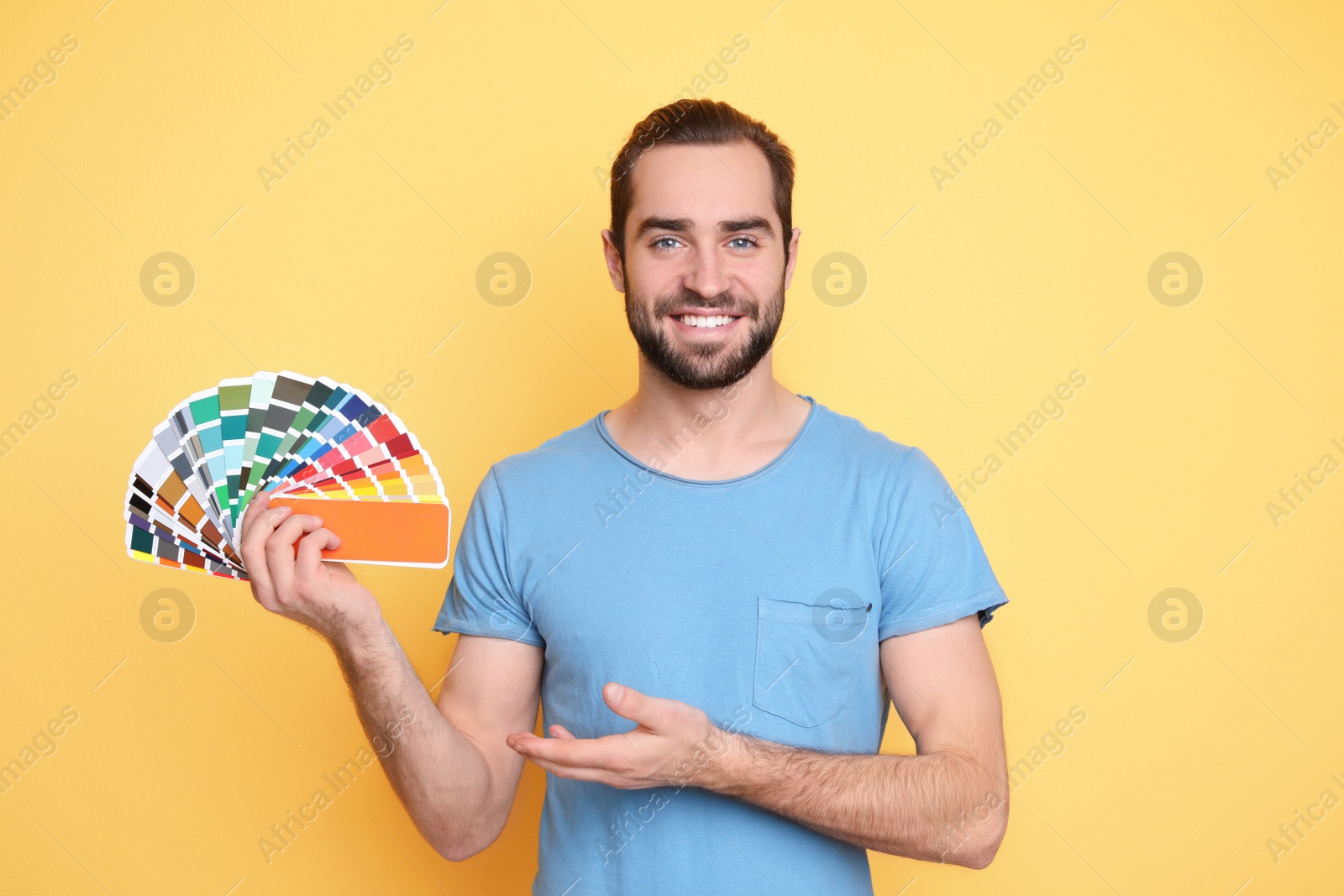 Photo of Young man with color palette on yellow background