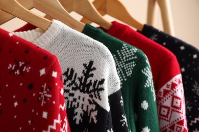 Photo of Different Christmas sweaters hanging on rack, closeup