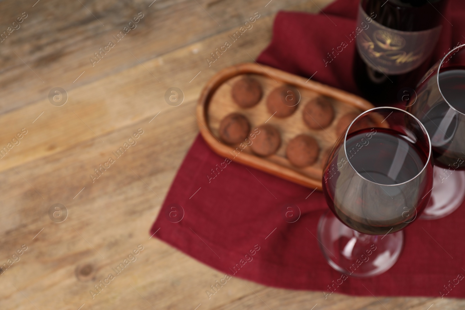 Photo of Red wine and chocolate truffles on wooden table, above view. Space for text