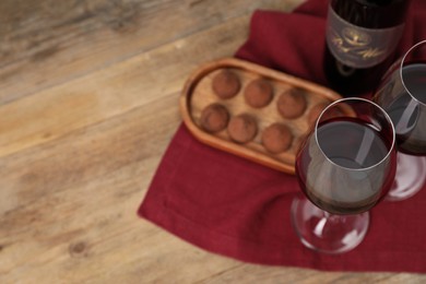 Red wine and chocolate truffles on wooden table, above view. Space for text