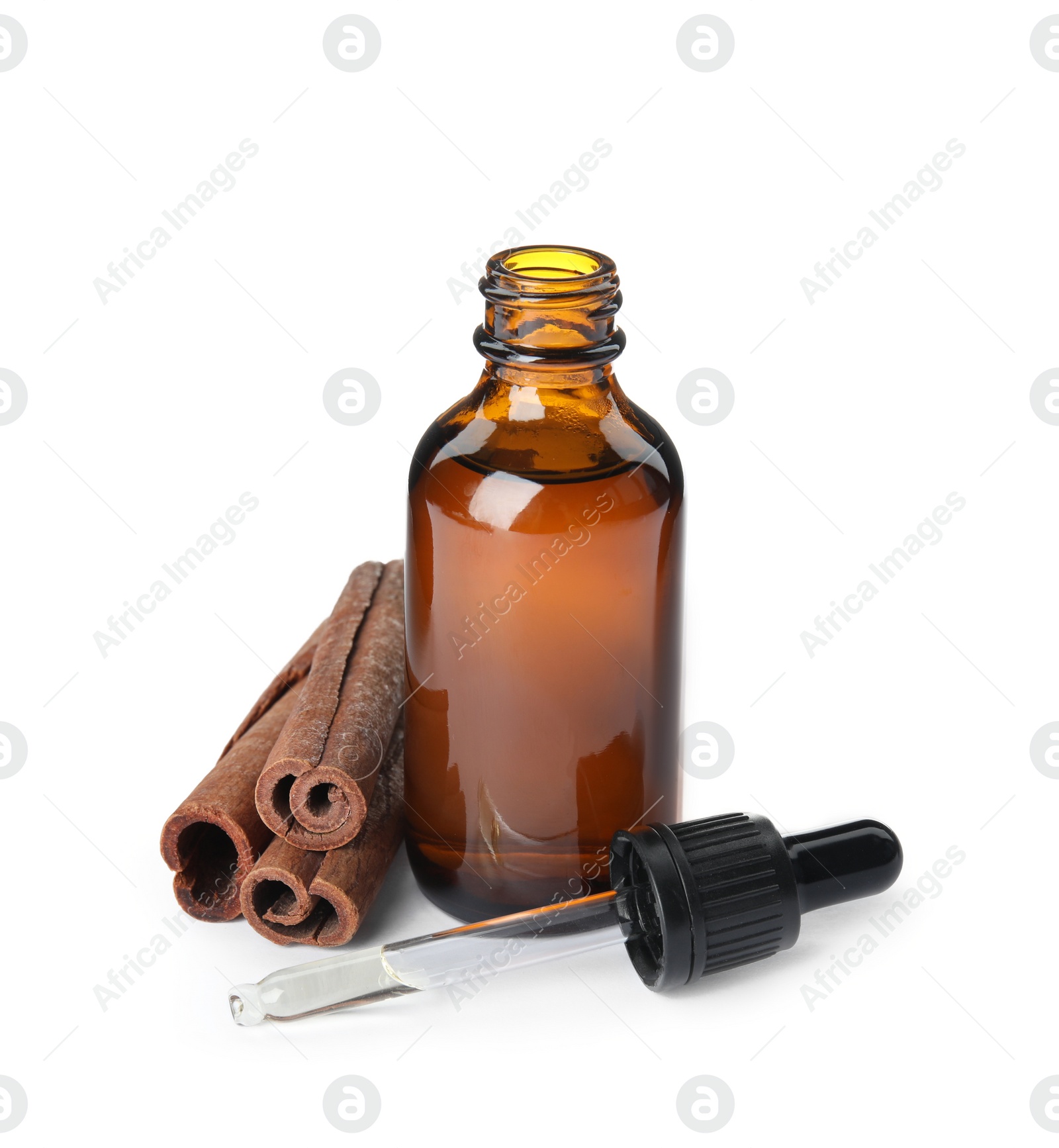 Photo of Bottle of essential oil and cinnamon sticks on white background