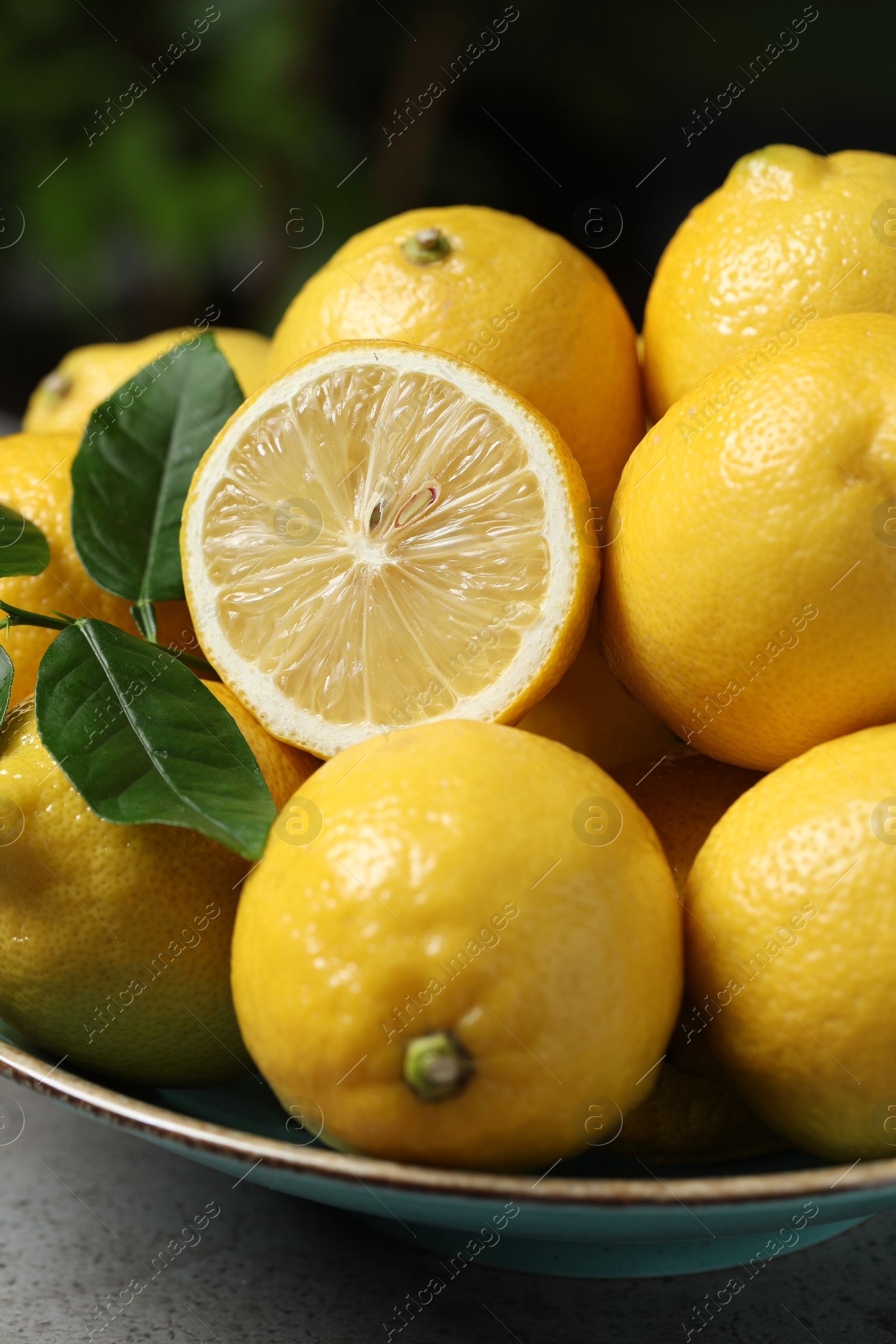 Photo of Fresh lemons and green leaves on grey table, closeup