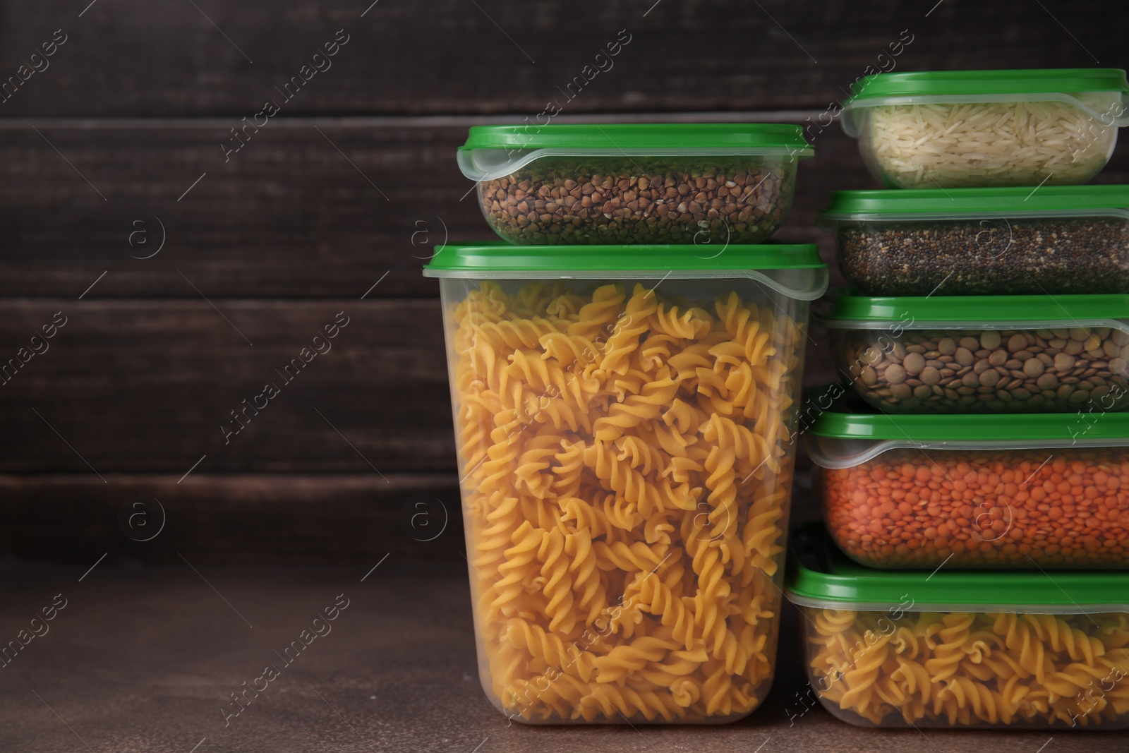 Photo of Plastic containers filled with food products on brown table. Space for text