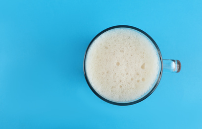 Photo of Delicious homemade kvass in glass mug on light blue background, top view. Space for text