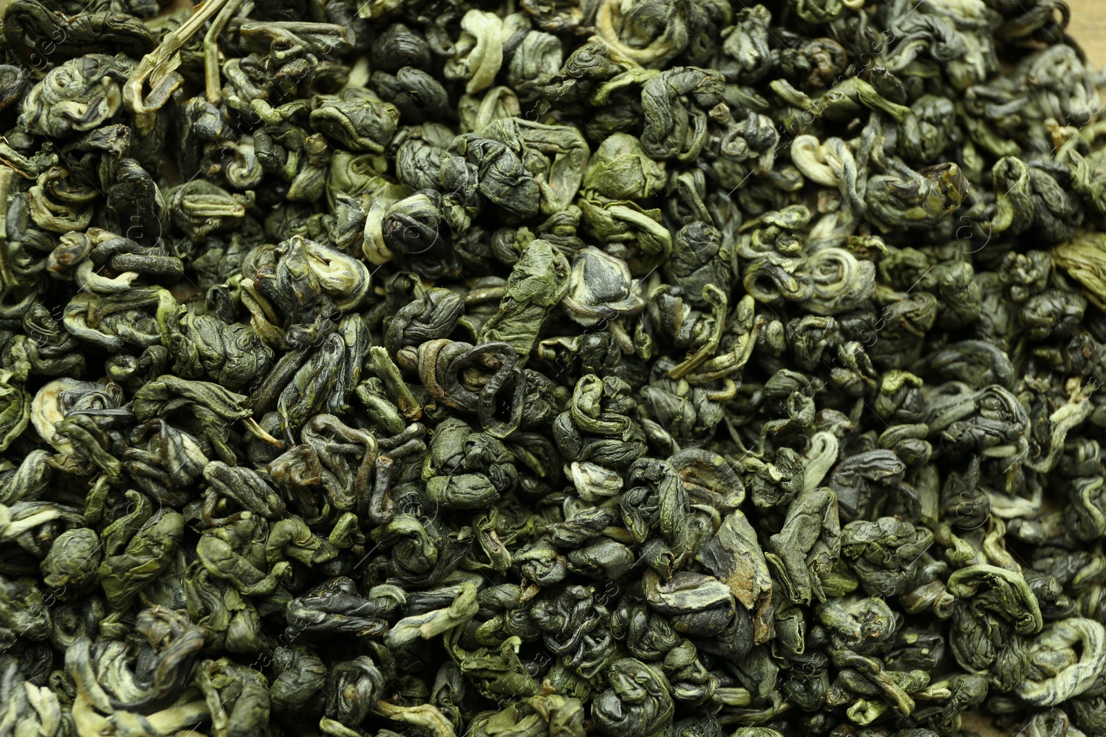 Photo of Dry green tea leaves as background, top view