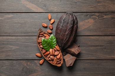 Flat lay composition with cocoa pods and chocolate on wooden table