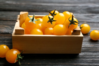 Photo of Ripe yellow tomatoes in crate on dark wooden table