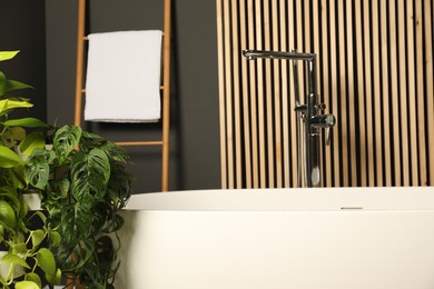 Photo of Spa day. Stylish bathroom interior with ceramic tub and green houseplants