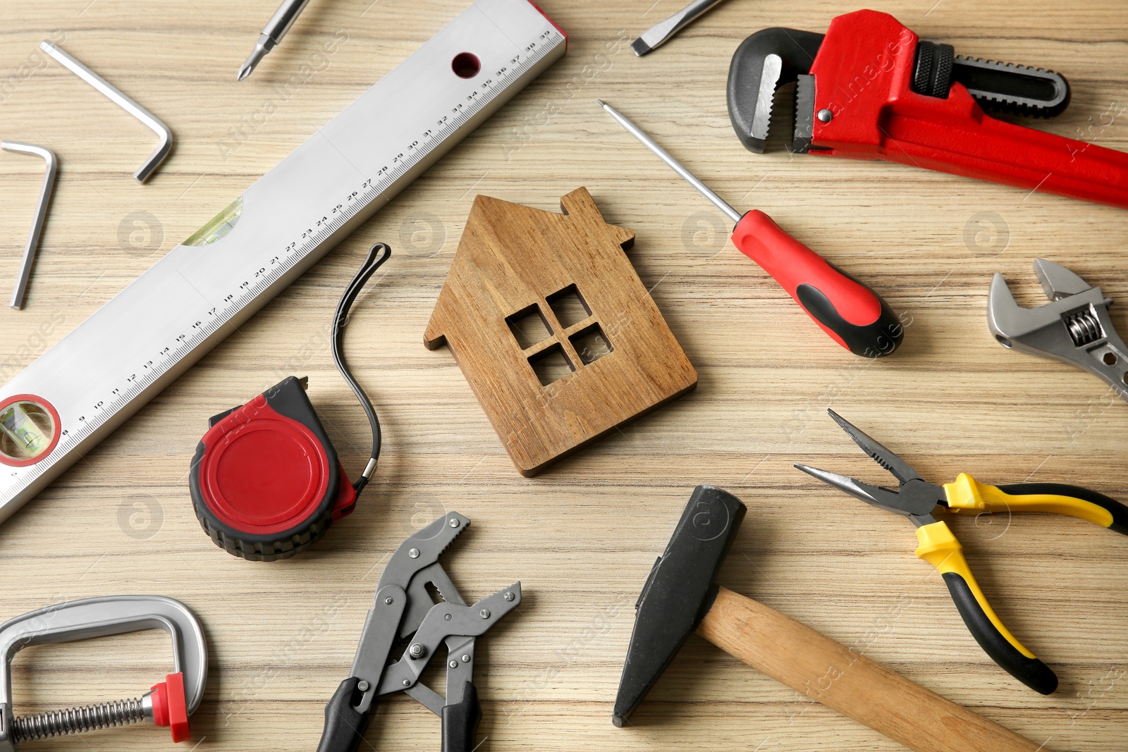 Photo of Composition with house figure and repair tools on wooden table, above view