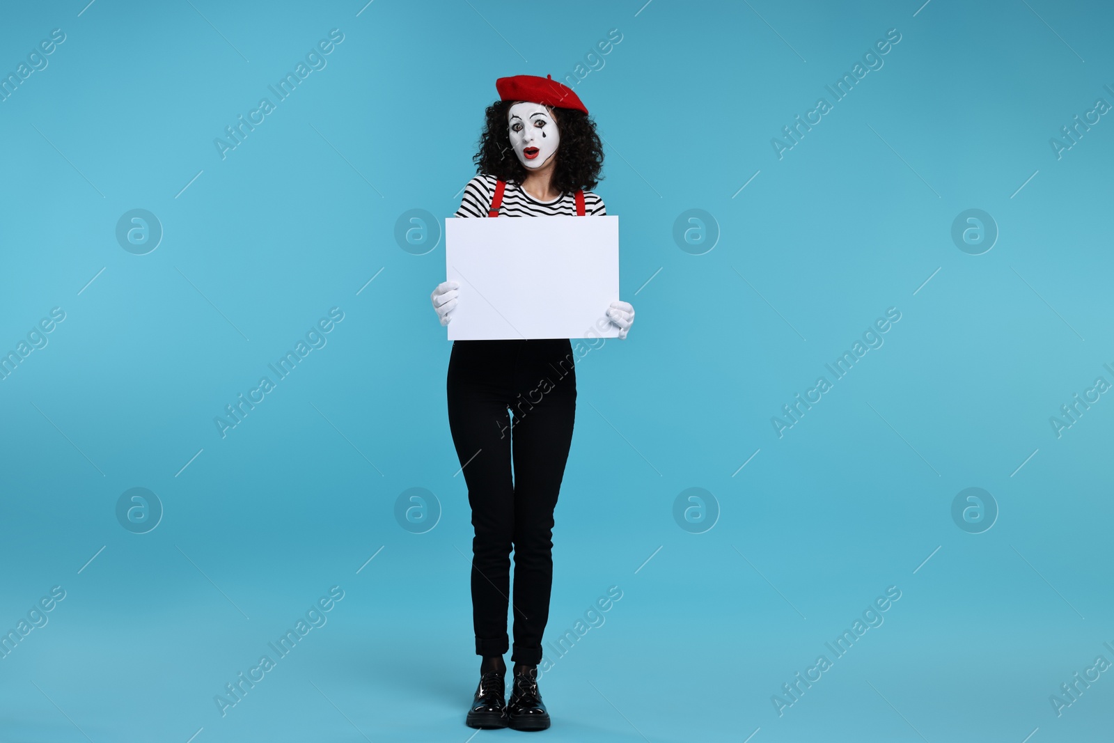 Photo of Funny mime with blank sign posing on light blue background
