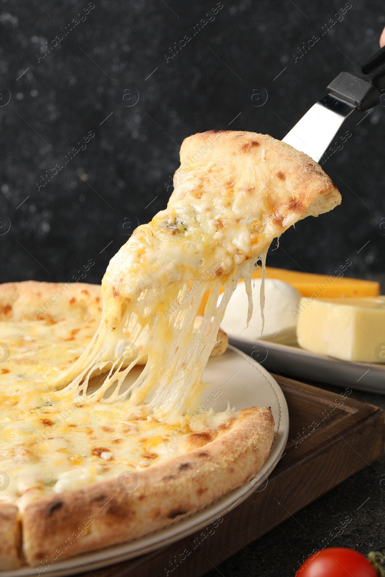 Photo of Taking piece of delicious cheese pizza at table, closeup