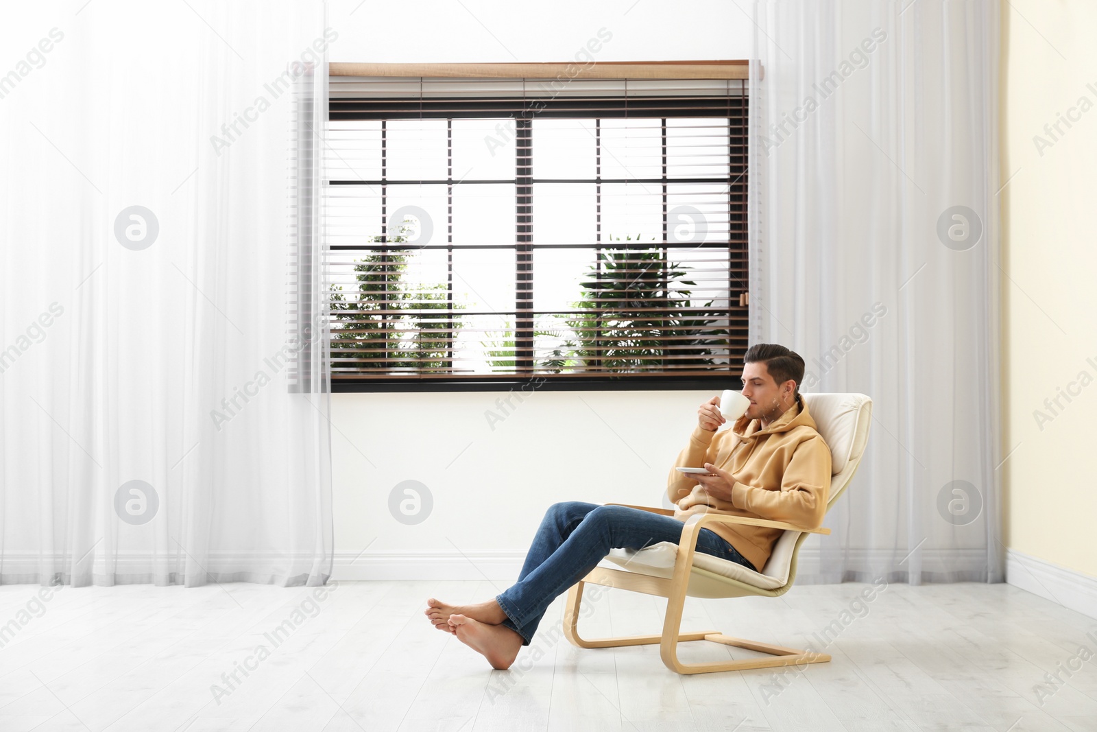 Photo of Attractive man relaxing in armchair near window at home. Space for text