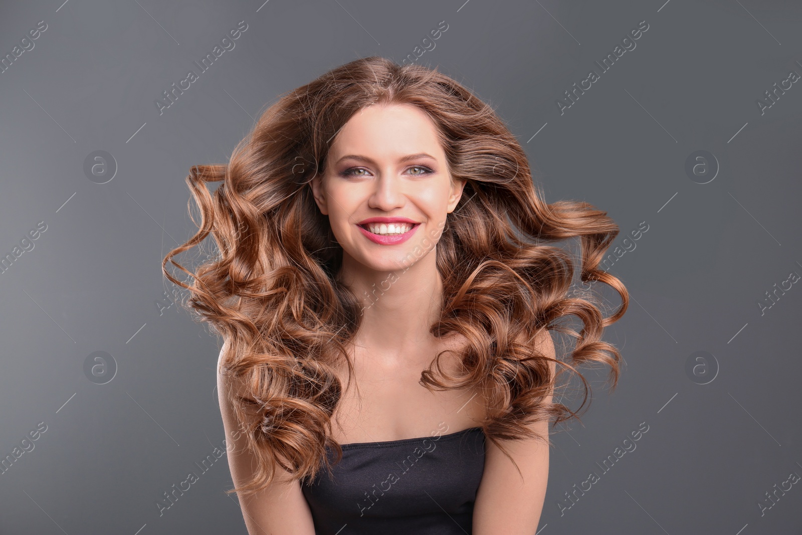 Photo of Portrait of young woman with long beautiful hair on grey background