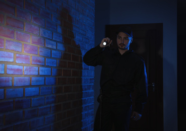 Male security guard with flashlight in dark corridor