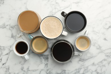 Photo of Different coffee drinks in cups on white marble table, flat lay