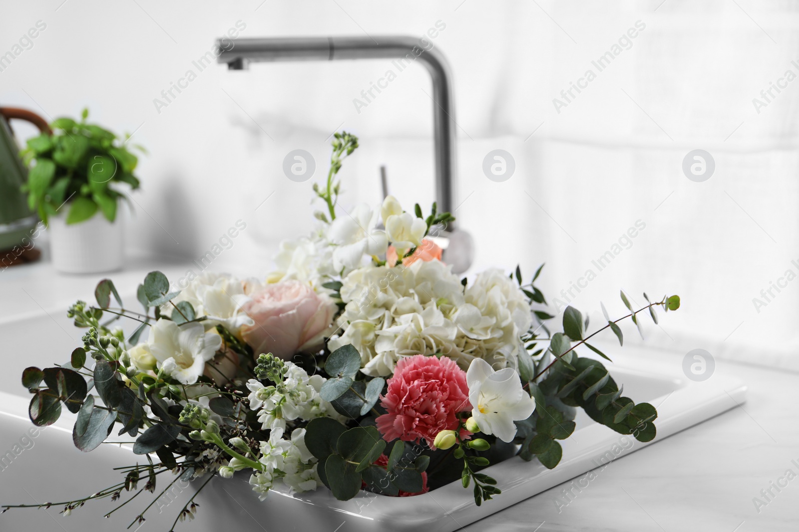 Photo of Bouquet of beautiful flowers in kitchen sink