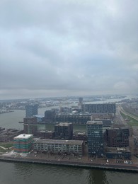 Picturesque view of city with modern buildings and harbor on cloudy day