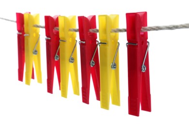 Colorful plastic clothespins hanging on rope against white background