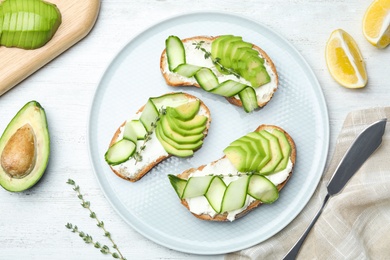 Photo of Flat lay composition with tasty avocado sandwiches on white wooden table