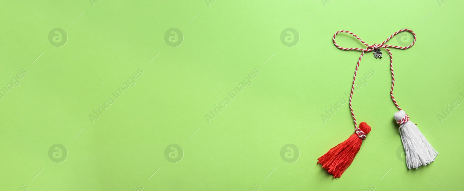 Photo of Traditional martisor on green background, top view with space for text. Beginning of spring celebration