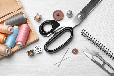 Photo of Flat lay composition with accessories for tailoring on wooden table