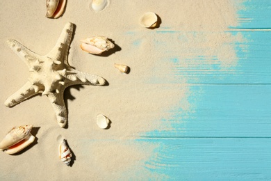 Flat lay composition with seashells, beach sand and space for text on wooden background