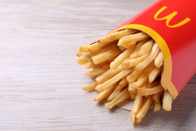 Photo of MYKOLAIV, UKRAINE - AUGUST 12, 2021: Big portion of McDonald's French fries on white wooden table, closeup. Space for text