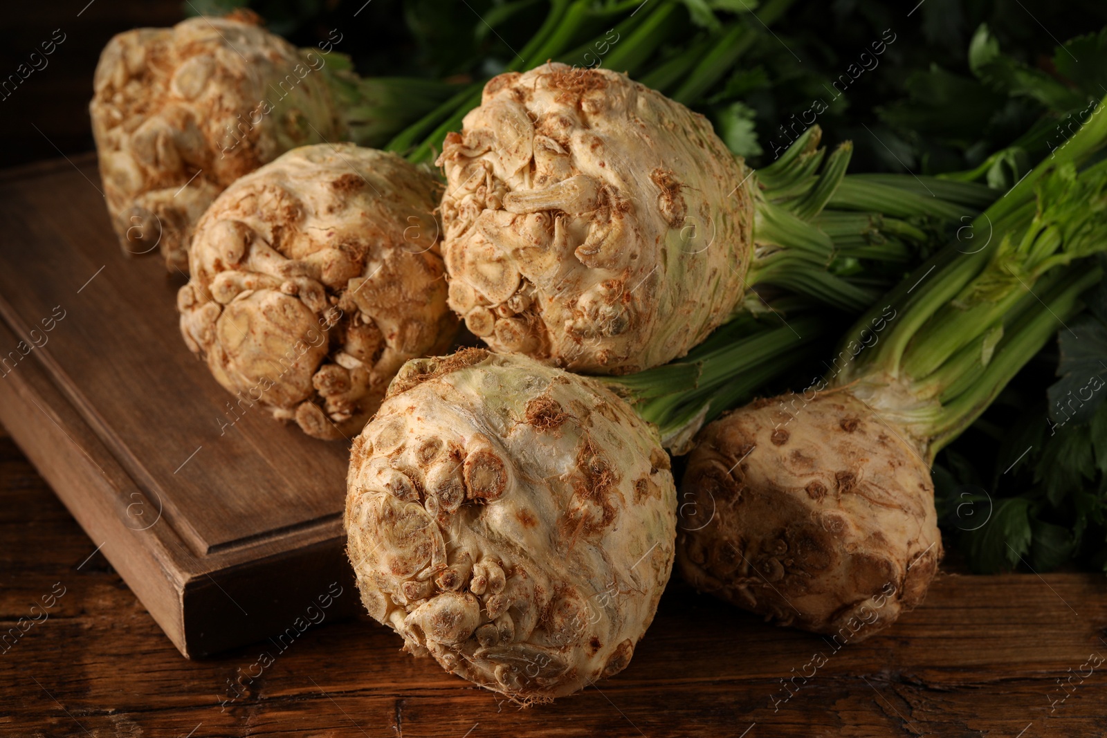 Photo of Fresh raw celery roots on wooden table, closeup