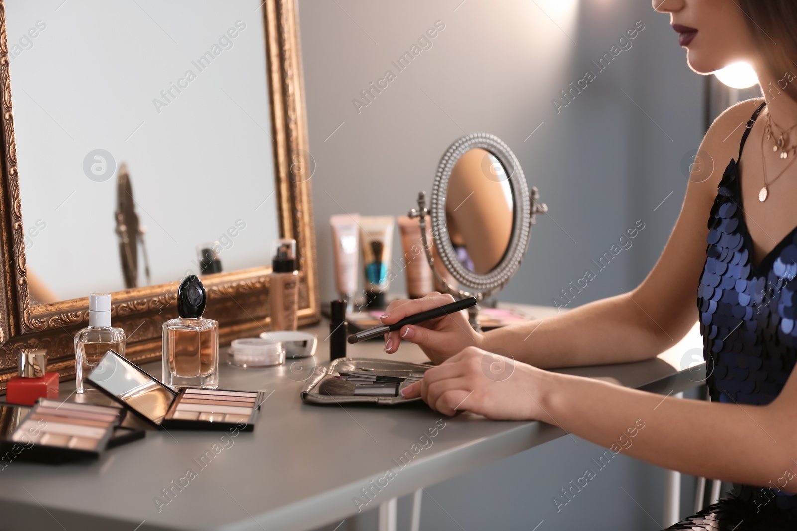 Photo of Young woman applying makeup indoors