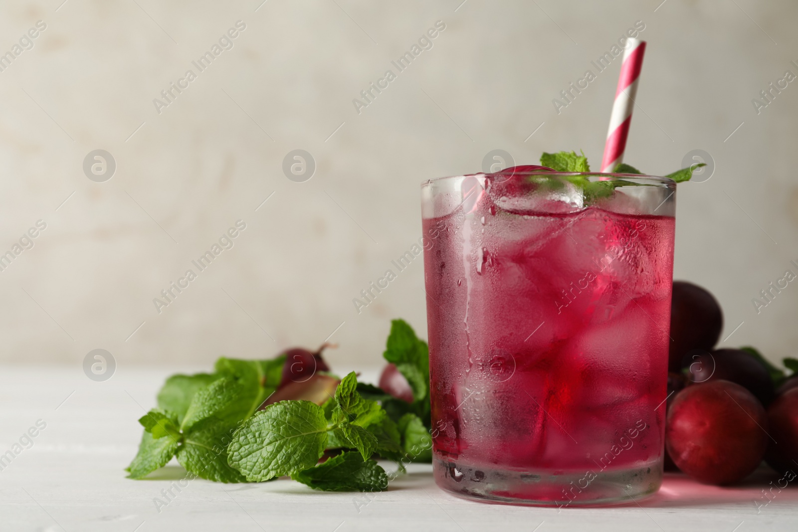 Photo of Delicious grape soda water with mint on white table. Refreshing drink