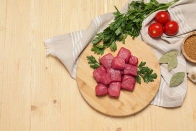 Photo of Raw beef meat and different ingredients for cooking delicious goulash on wooden table, flat lay. Space for text