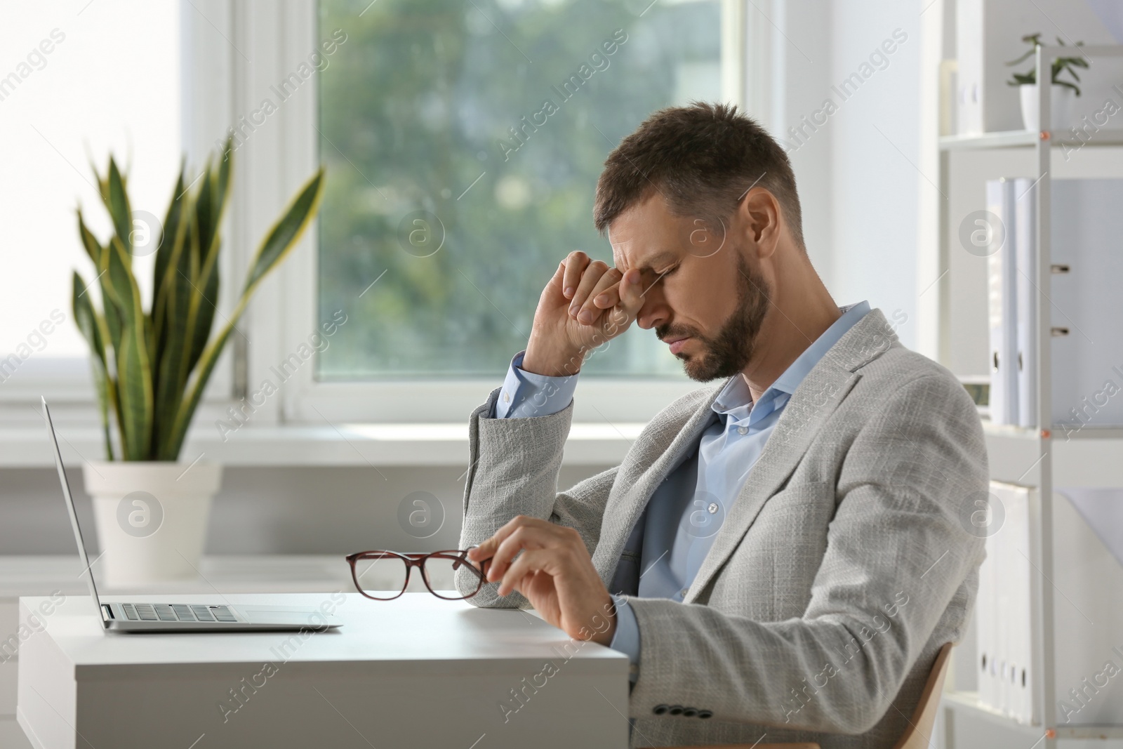 Photo of Man suffering from eyestrain at desk in office