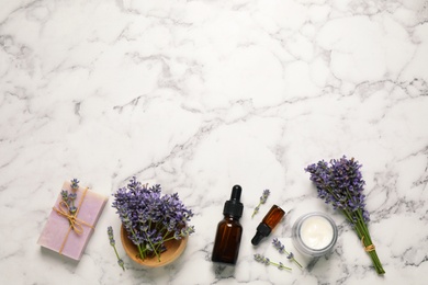 Photo of Cosmetic products and lavender flowers on white marble table, flat lay. Space for text