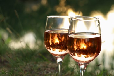 Photo of Glasses of tasty rose wine on blurred background, closeup and space for text. Picnic season